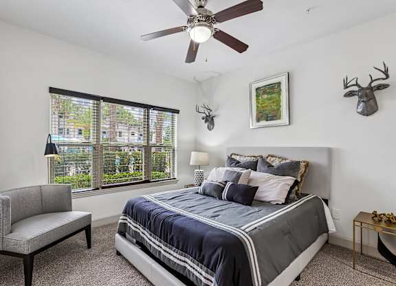 A bedroom with a bed, a chair, and a ceiling fan.