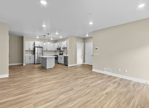 a spacious living room with a kitchen in the background