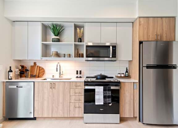 A modern kitchen with a refrigerator, microwave, and oven.