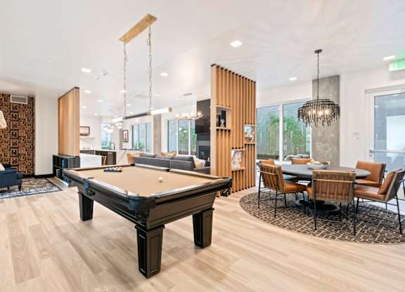 A pool table is in the middle of a room with a dining table and chairs.