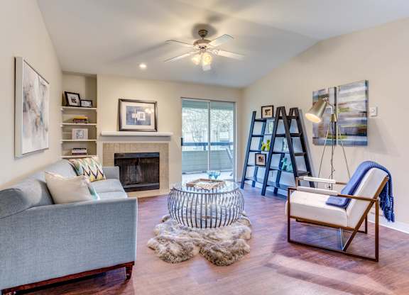 A living room with a grey couch, a fireplace, and a chair with a blue throw.