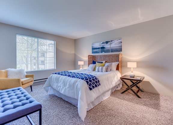 A bedroom with a large bed and a chair.