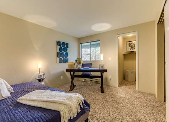 A bedroom with a bed, a desk, and a chair.