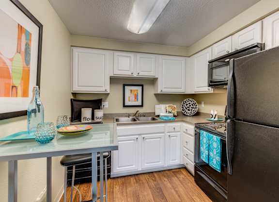 A kitchen with white cabinets and a black refrigerator.