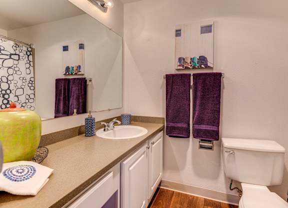A bathroom with a white tub and purple towels.