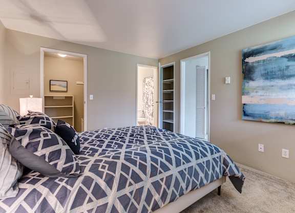 A bedroom with a large bed and a painting on the wall.