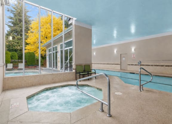 A hot tub sits in a room with a glass wall.