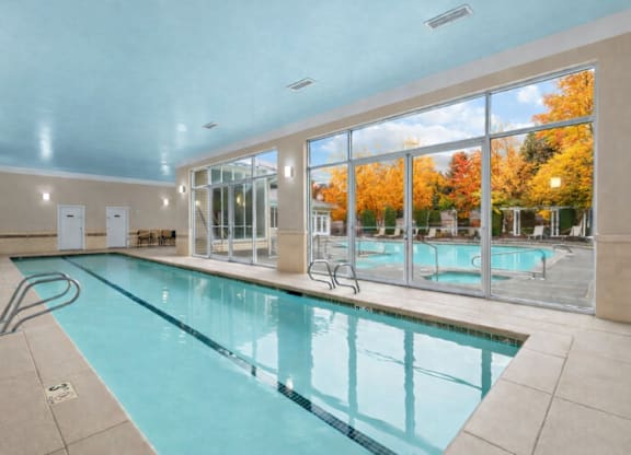 A large indoor swimming pool with a view of the outdoors through the windows.