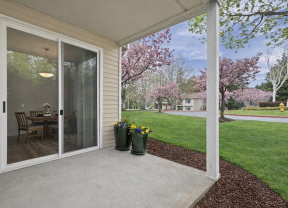 A patio with a table and chairs is covered by a glass door.