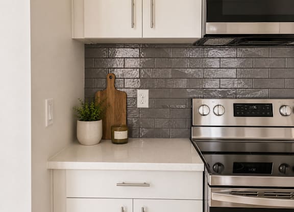 A kitchen with a stove and a cutting board on the counter.