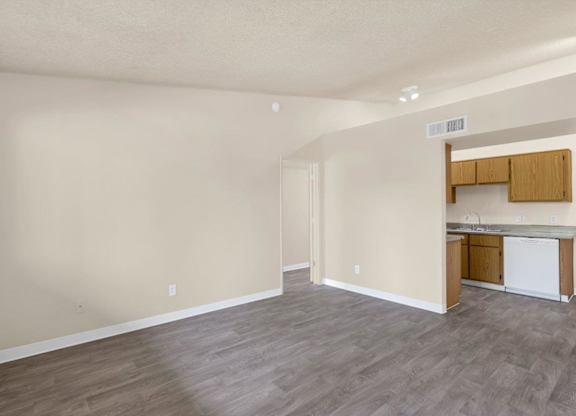 A kitchen area with a white dishwasher and wooden cabinets.