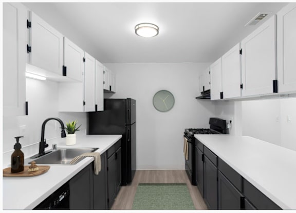 A kitchen with black cabinets and white countertops at The Rosewood Apartments in Vancouver, Washington.