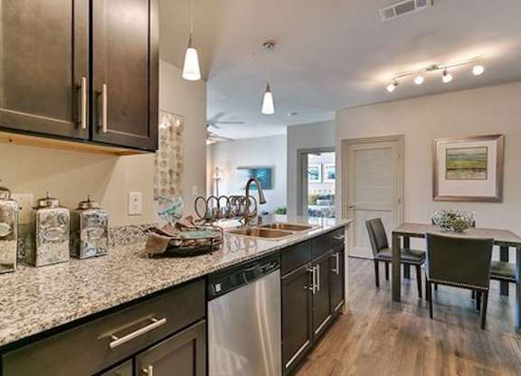 A kitchen with dark wood cabinets and granite countertops.