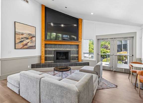 A living room with a grey couch and a fireplace.