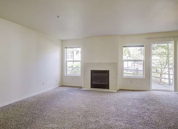 A living room with a fireplace and carpeted floor.