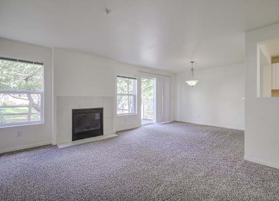 A living room with a fireplace and carpeted floor.