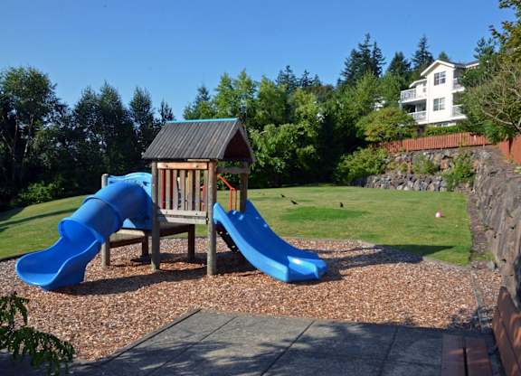 A playground with a blue slide and a wooden structure.