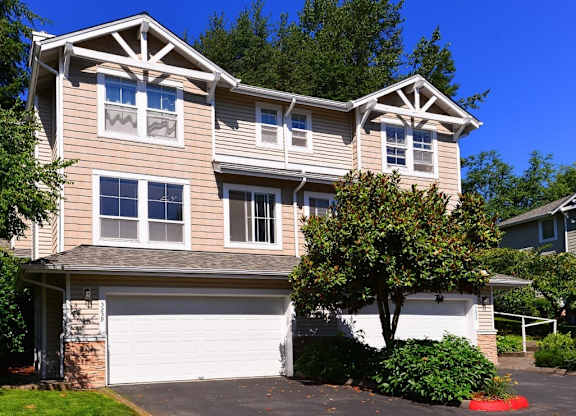A two-story house with a garage and a tree in front.