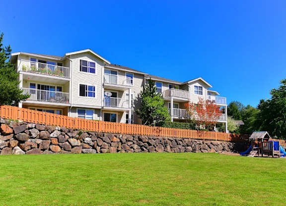 A large apartment building with a stone wall in front.
