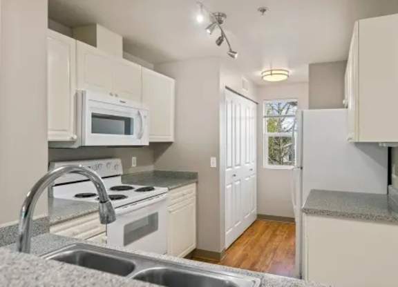 A kitchen with white cabinets and a stove top oven.