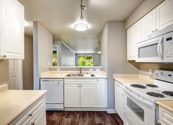 A kitchen with white cabinets and appliances.