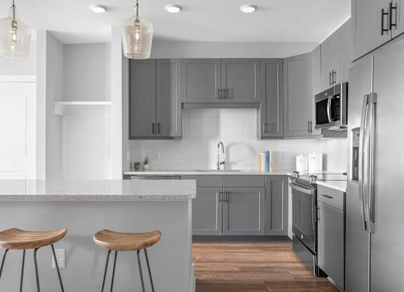 A modern kitchen with a white countertop and grey cabinets.