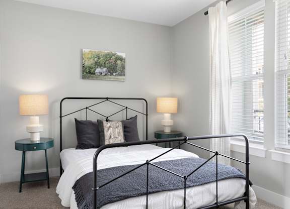 A bedroom with a black metal bed frame and a white bedspread.