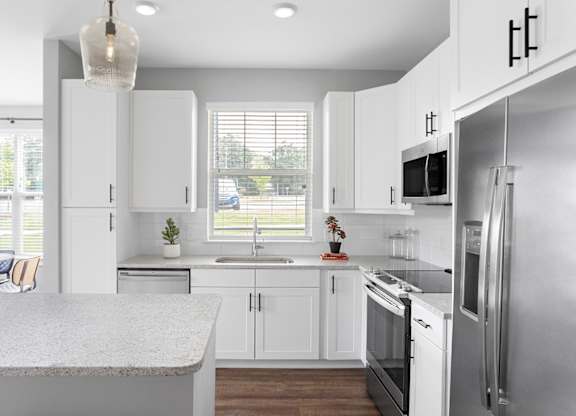 A modern kitchen with white cabinets and stainless steel appliances.