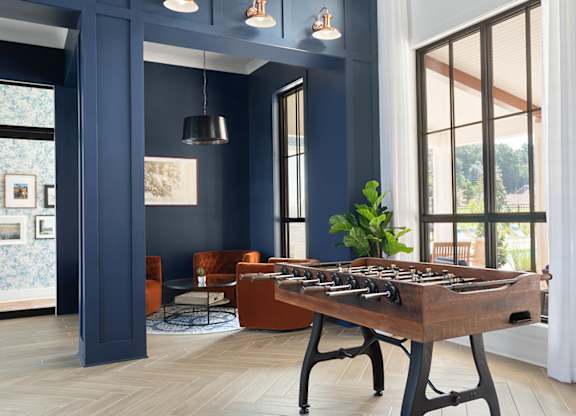A foosball table sits in the middle of a room with blue walls and a large window.