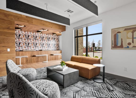 a living room with a brown couch and a black and white rug