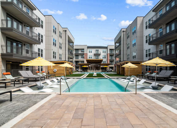an outdoor pool with lounge chairs and umbrellas at the bradley braddock road