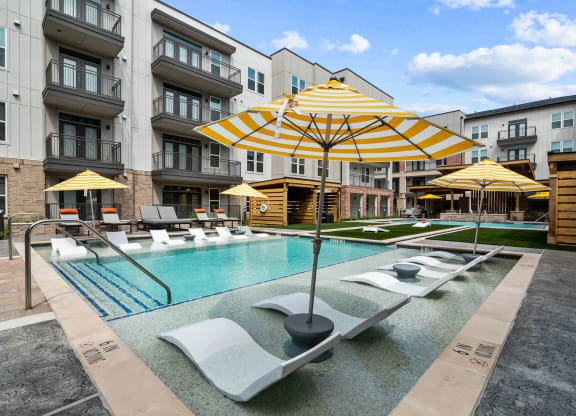 a swimming pool with yellow umbrellas and white lounge chairs