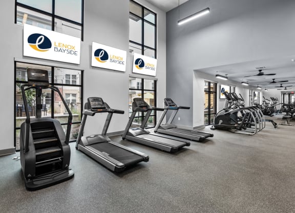 a gym with treadmills and other exercise equipment in a building with large windows