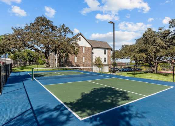 A tennis court with a blue surface and white boundary lines.
