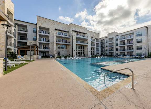 A large swimming pool is surrounded by apartment buildings.