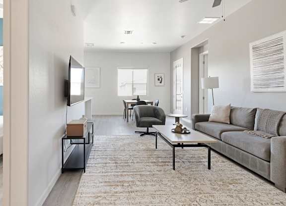 A living room with a grey couch and a white bed.