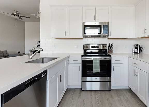 A modern kitchen with white cabinets and stainless steel appliances.