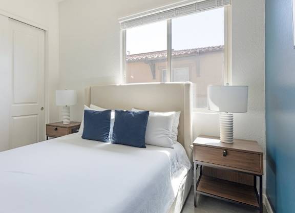 A bedroom with a large bed, two lamps, and a nightstand.