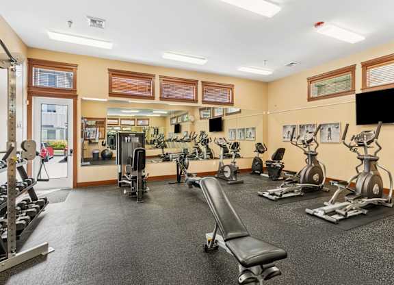 A gym with a variety of equipment including treadmills, weights, and exercise machines.