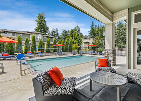 A patio with a table and chairs overlooking a pool.