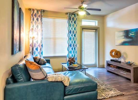 A living room with a blue couch and a ceiling fan.