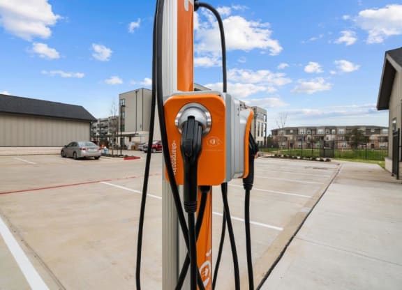 an orange electric charger plugged into a parking lot