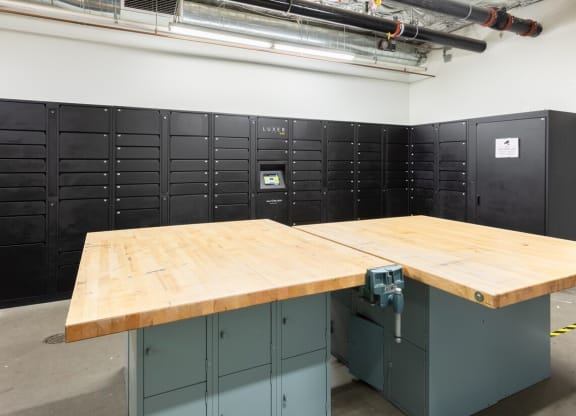 a large wooden table sits in the middle of a room full of black lockers