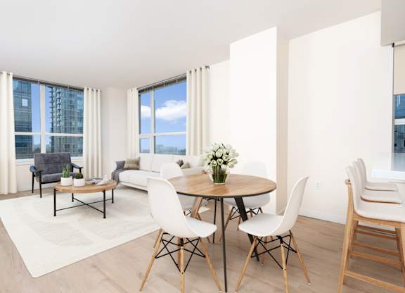 A modern dining room with a round table and white chairs.