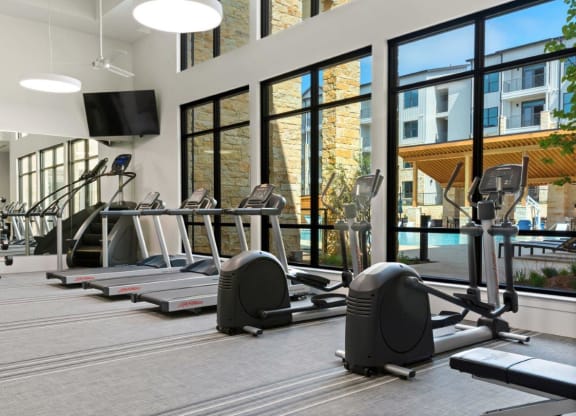 a gym with cardio equipment and windows in a building