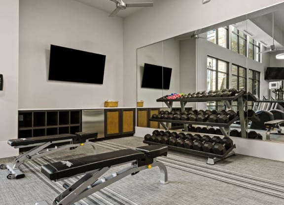 a gym with weights and mirrors in front of a large mirror