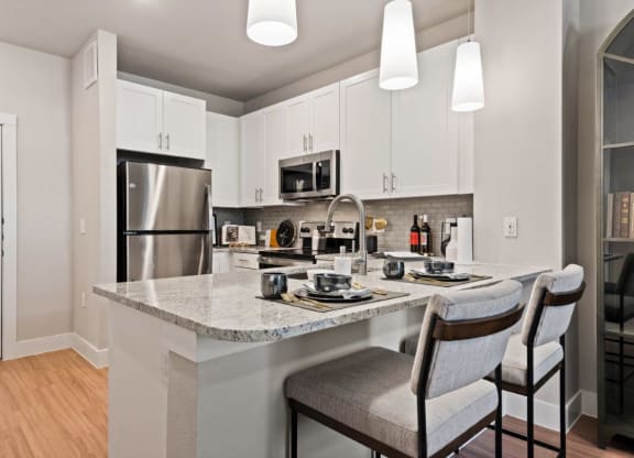 a kitchen with a marble counter top and a stainless steel refrigerator