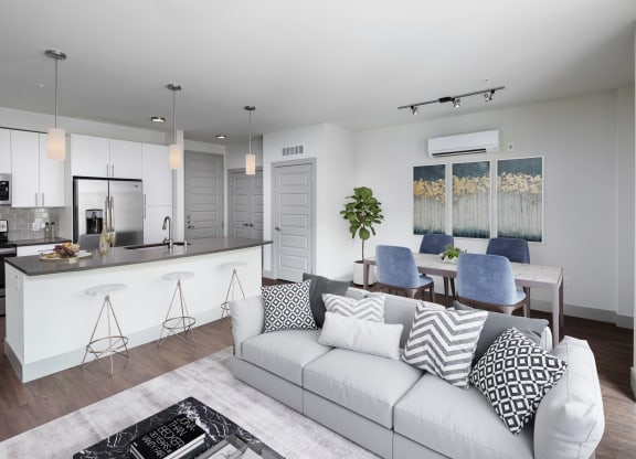 a living room with a white couch and a kitchen with a bar