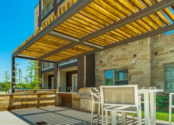 A patio with a table and chairs is covered by a wooden roof.