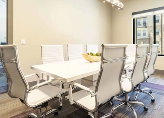 A conference room with a white table and chairs.